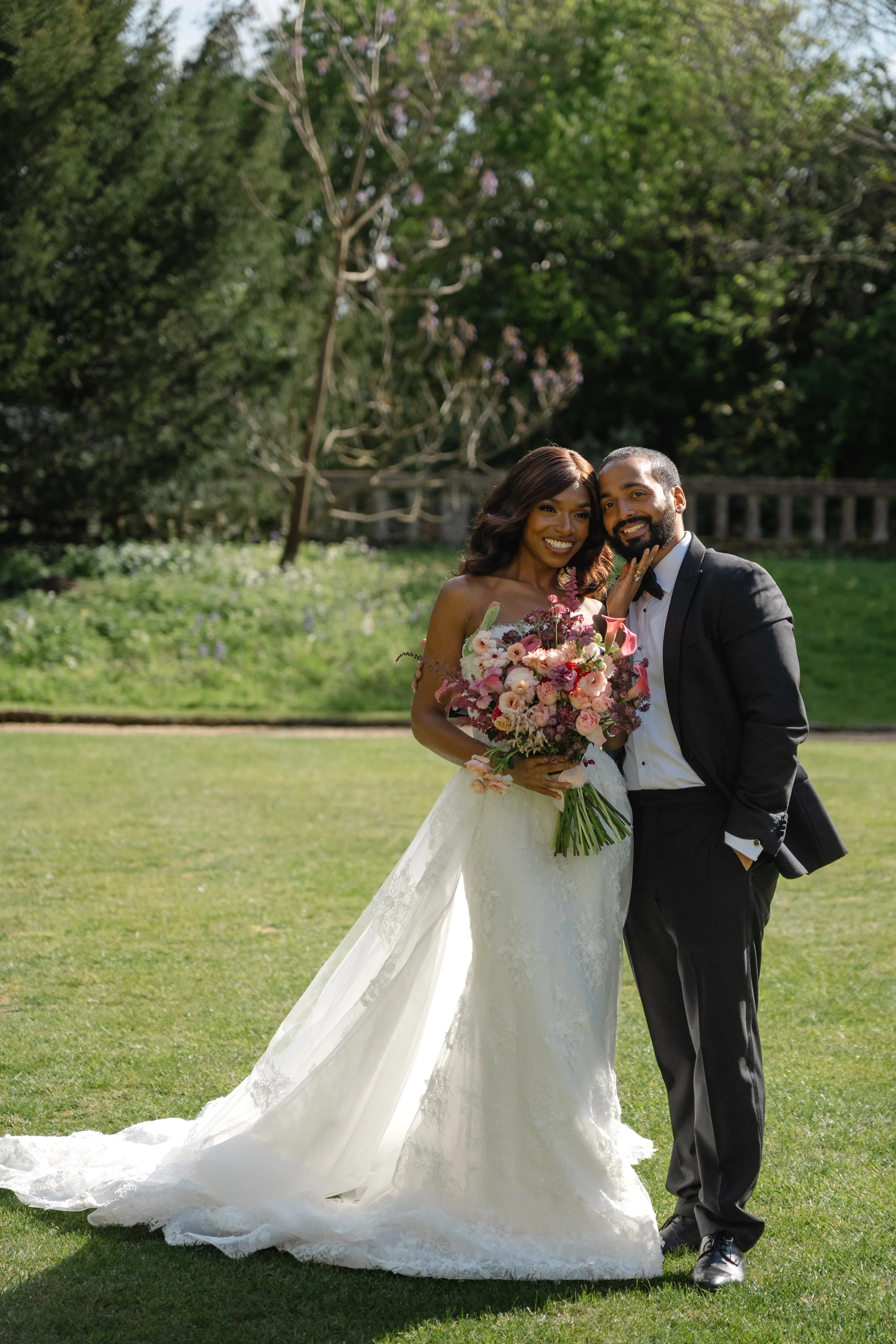bride and groom standing with their bouquet of flowers in the garden of their wedding
