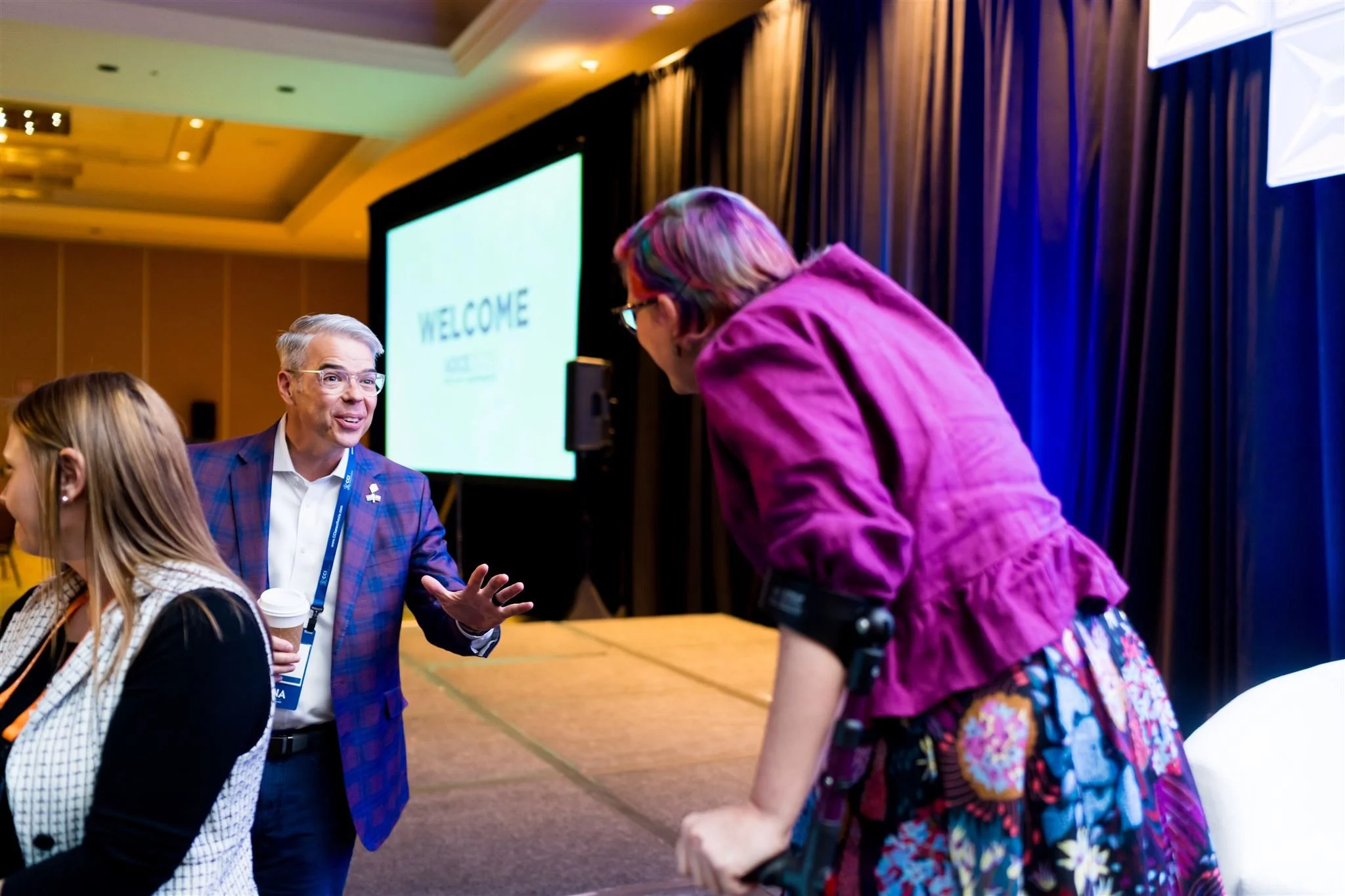 Rebecca leans down from the stage to talk with a conference attendee.