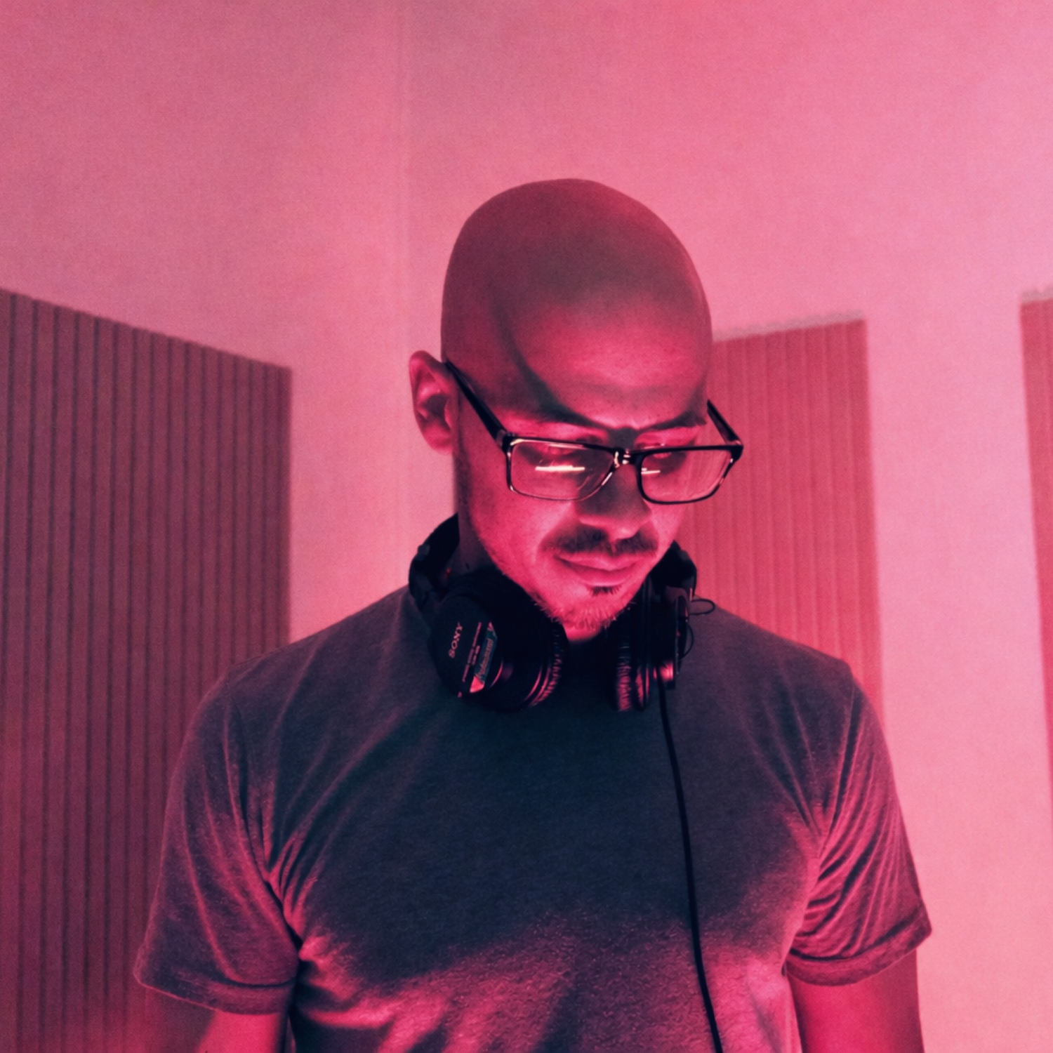 American uplifting trance producer with glasses looks thoughtfully while composing electronic dance music (EDM). Underground techno, house, trance scene. Modern.