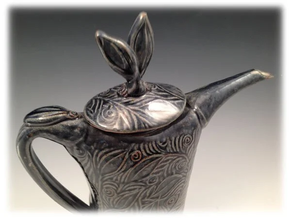 Ceramic teapot with bunny-shaped lid and decorative swirling patterns, black and gray finish.