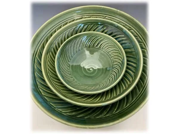 Set of green glass nesting bowls with spiral and leaf patterns.