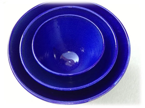 Two blue plastic bowls nested inside each other on a light surface.