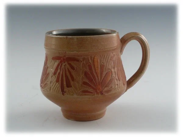 A ceramic mug with a floral pattern and a handle, set against a plain background.