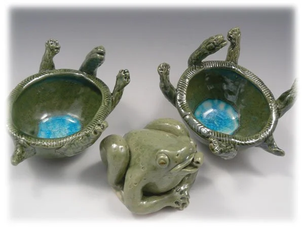 Decorative ceramic turtle-shaped planters with a ceramic frog figurine in front.