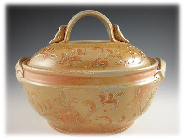 A ceramic soup tureen with a lid, decorated with orange and beige floral patterns.
