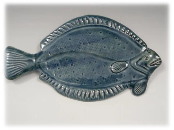A ceramic fish-shaped decorative object with a blue and gray glaze.