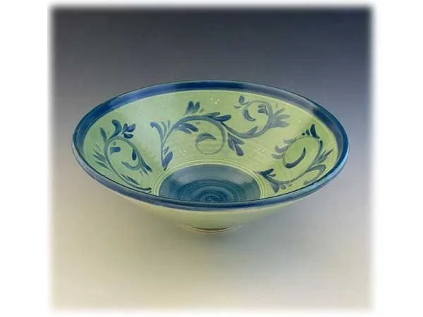 A decorative ceramic bowl with a green interior and blue floral and leaf patterns.