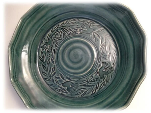 Green ceramic bowl with embossed leaf, branch, and rabbit patterns inside