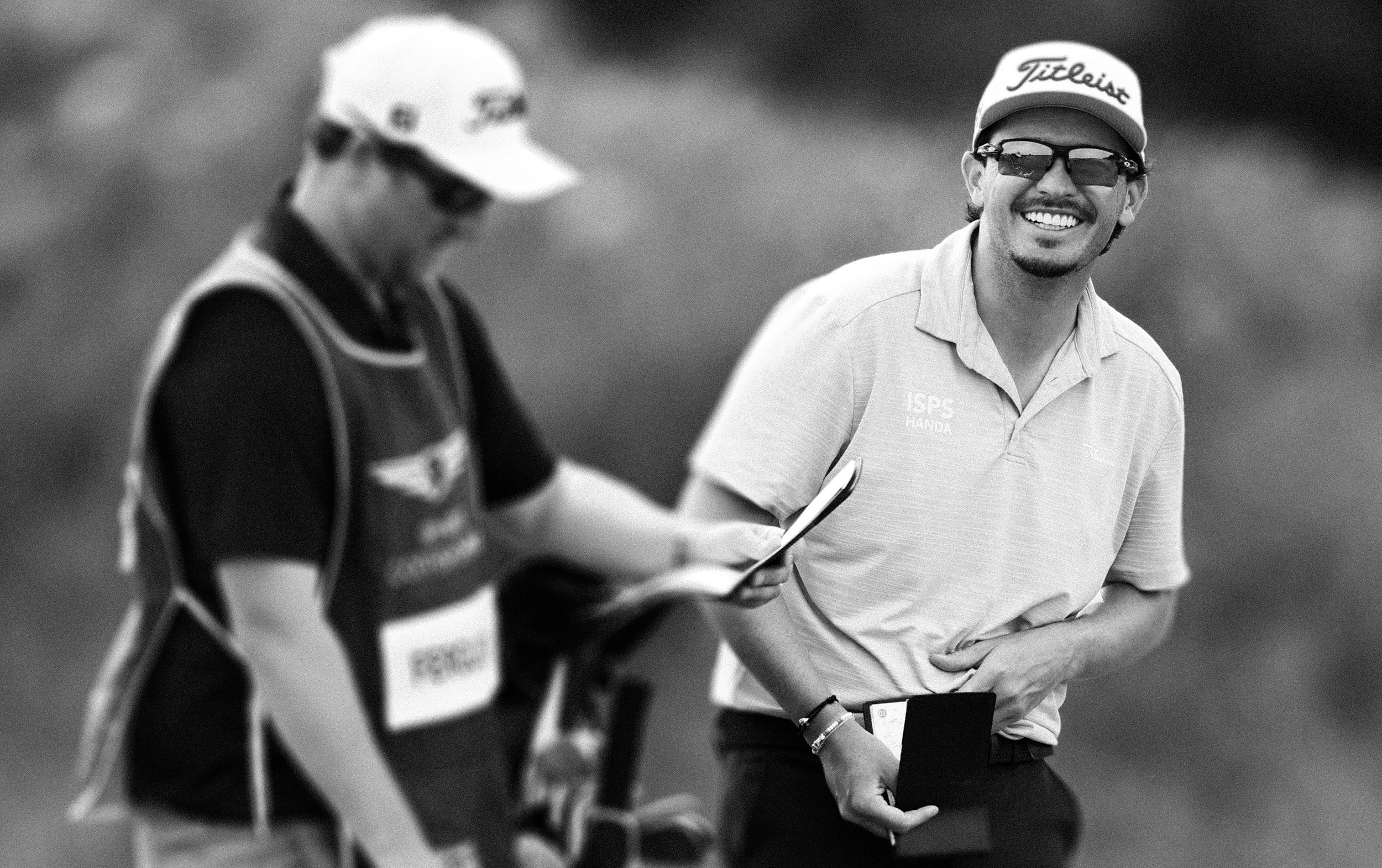 Ewen Ferguson standing on a golf course with a cap and glasses smiling