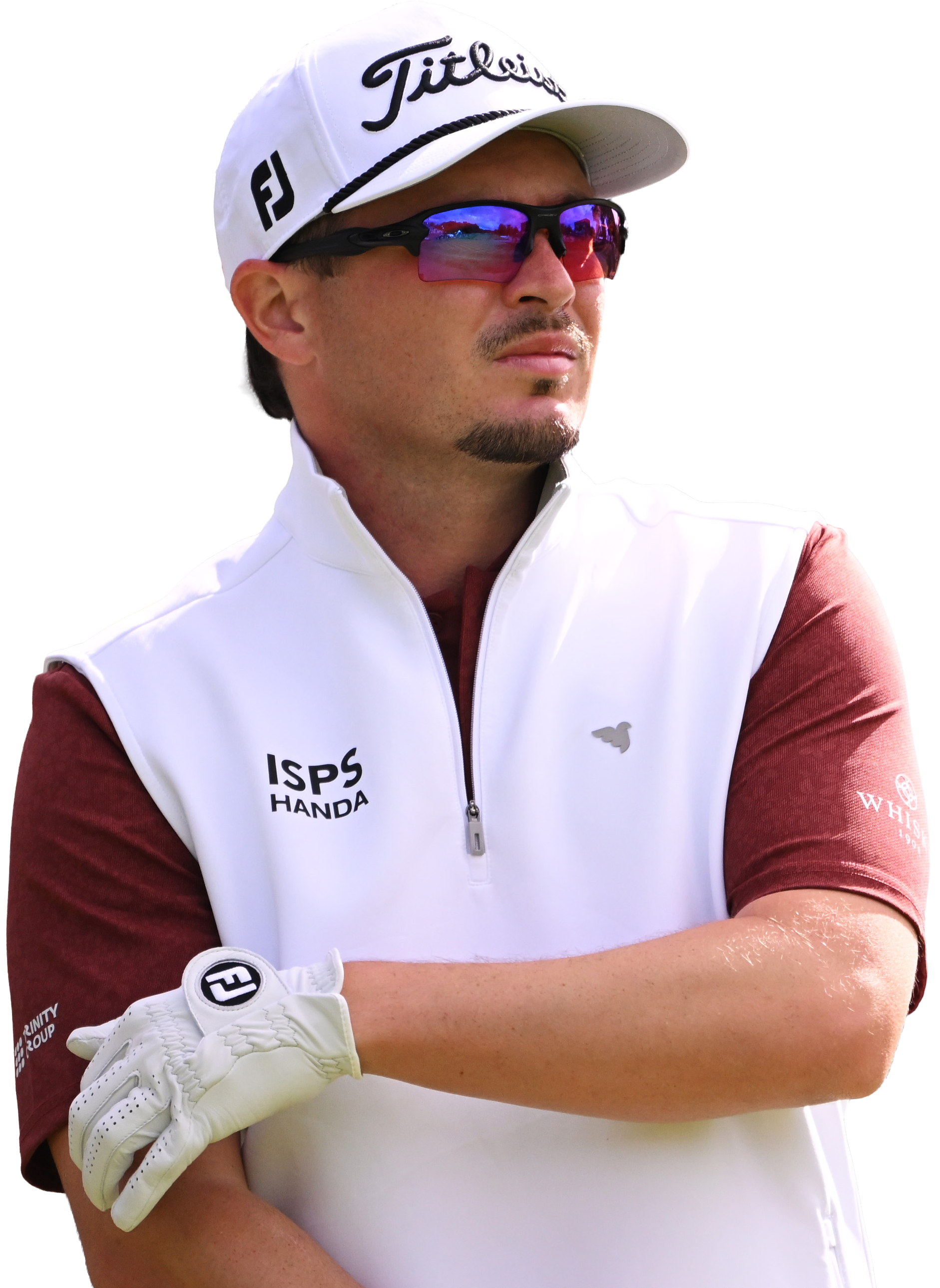 Ewen Ferguson wearing a white Titleist cap, sports sunglasses reflecting a golf course, a white vest with 'ISPS HANDA' logo, and a maroon shirt with a logo on the sleeve, is crossing his arms, with his left arm visible.