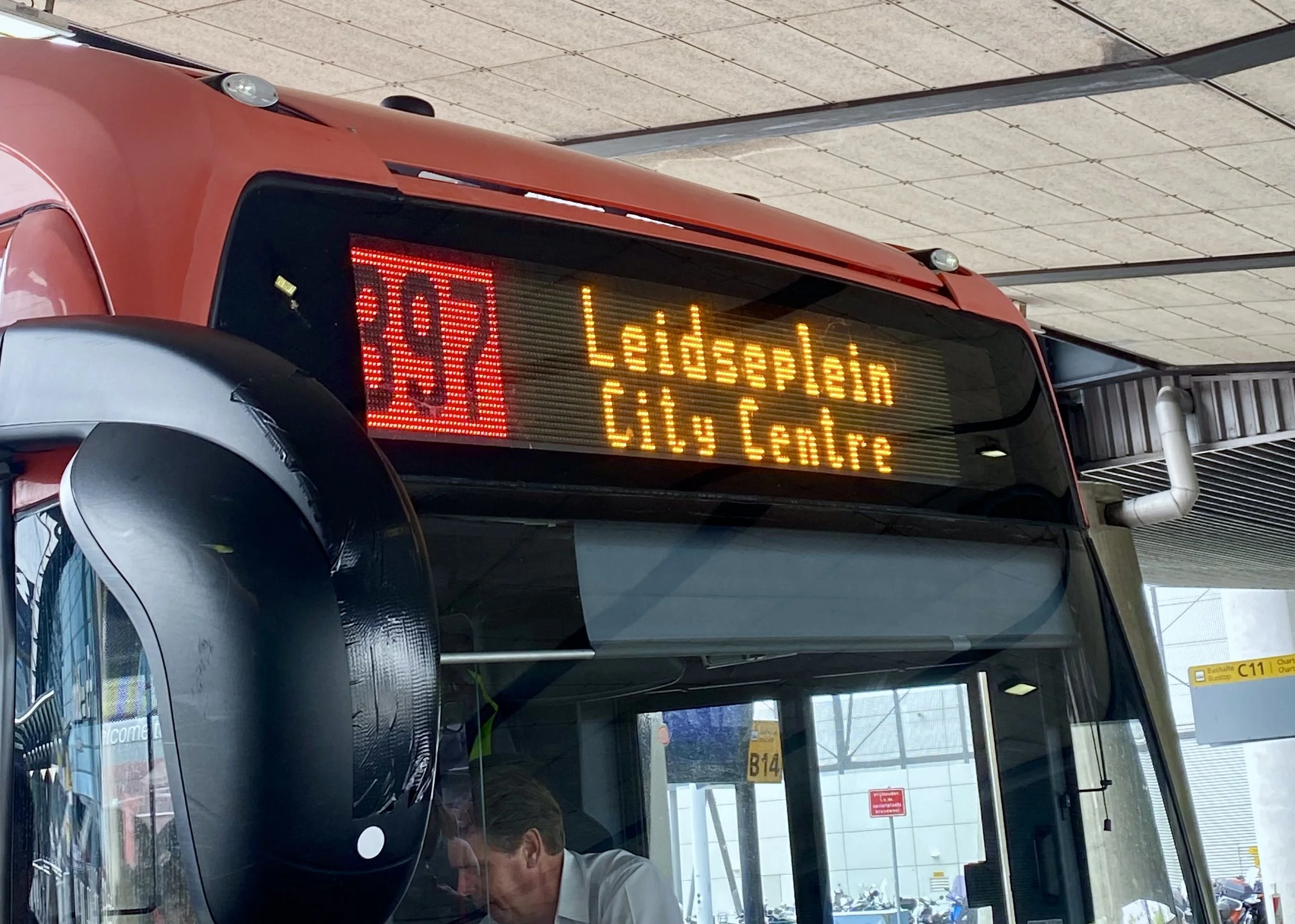 Digital display on a bus showing route 355 to Lidsaplein and Calle Central, with part of the bus's mirror and interior visible.