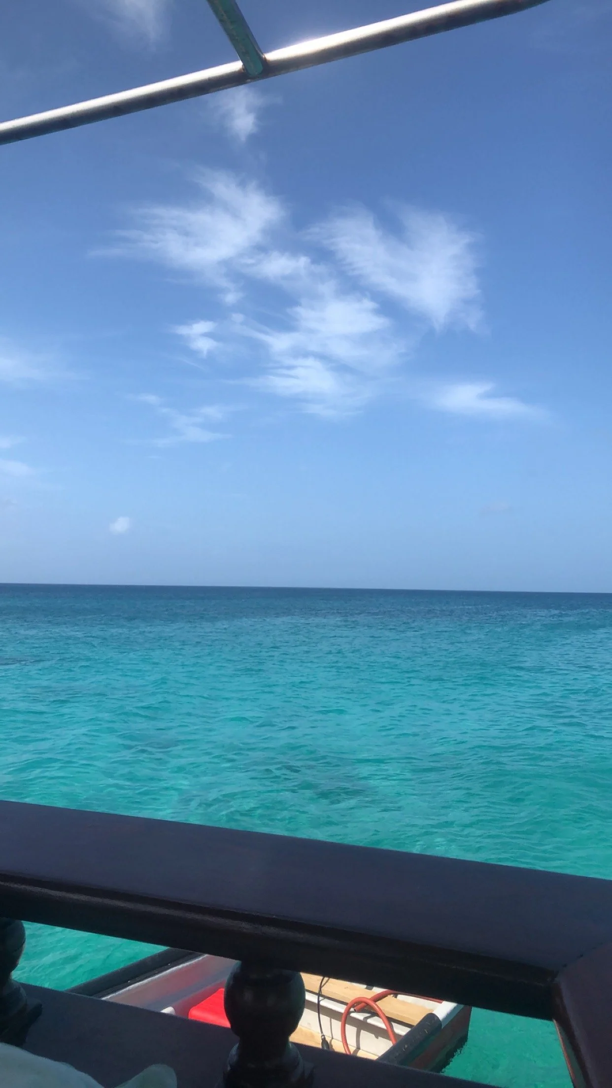 View of the ocean with blue water and a clear sky with some clouds, seen from a boat or watercraft.