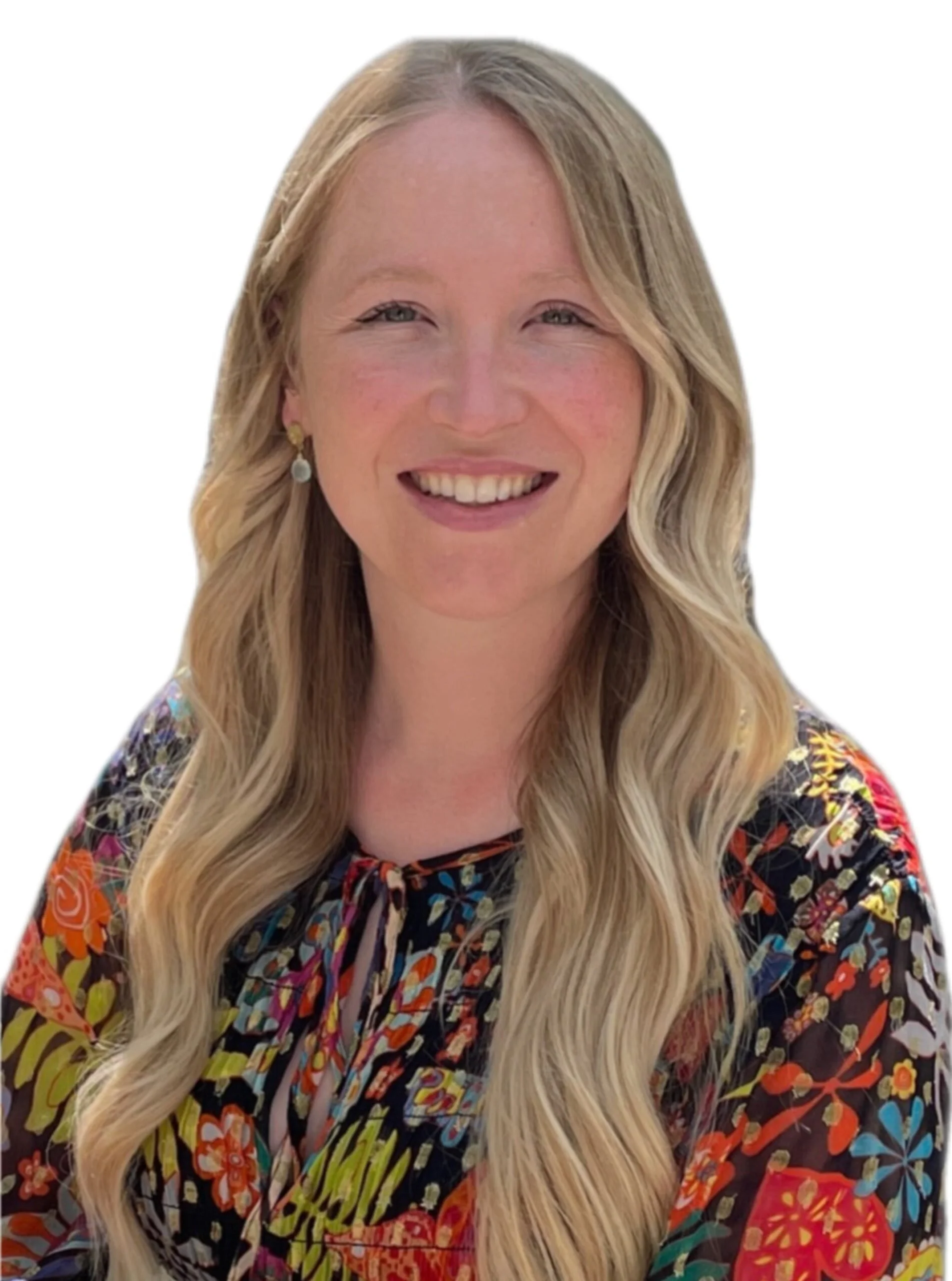 A woman with long blonde hair wearing a colorful, floral-patterned top and gold earrings, smiling against a white background.