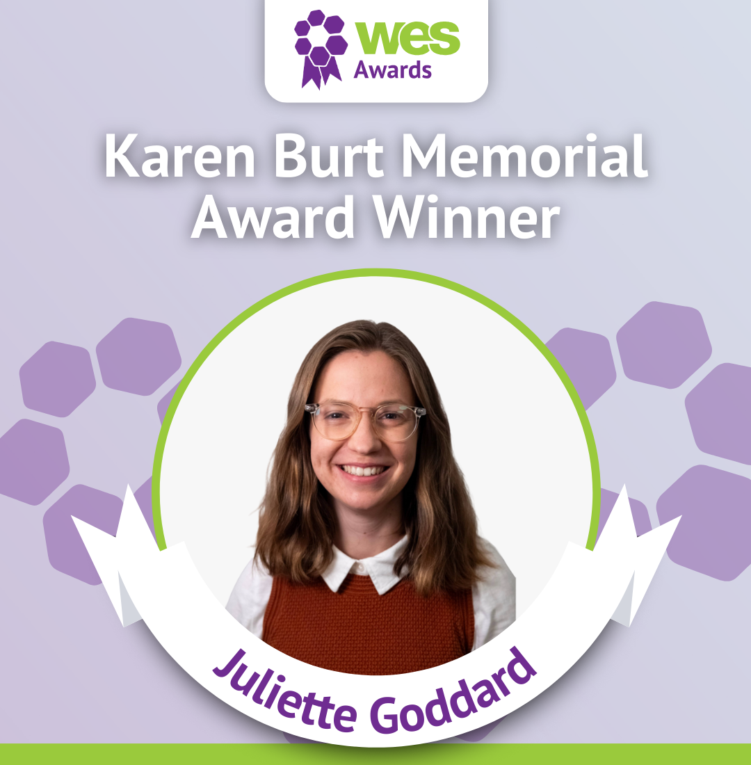 Photograph of Juliette Goddard, smiling woman with glasses, wearing a white blouse and brown vest, labeled as Karen Burt Memorial Award Winner at the Wes Awards with purple and green design elements.