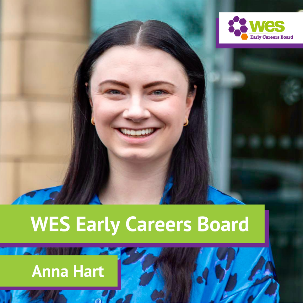 A woman with long dark hair smiling outdoors, wearing a blue animal print top, with a logo for WES Early Careers Board and her name, Anna Hart, displayed on a green banner.