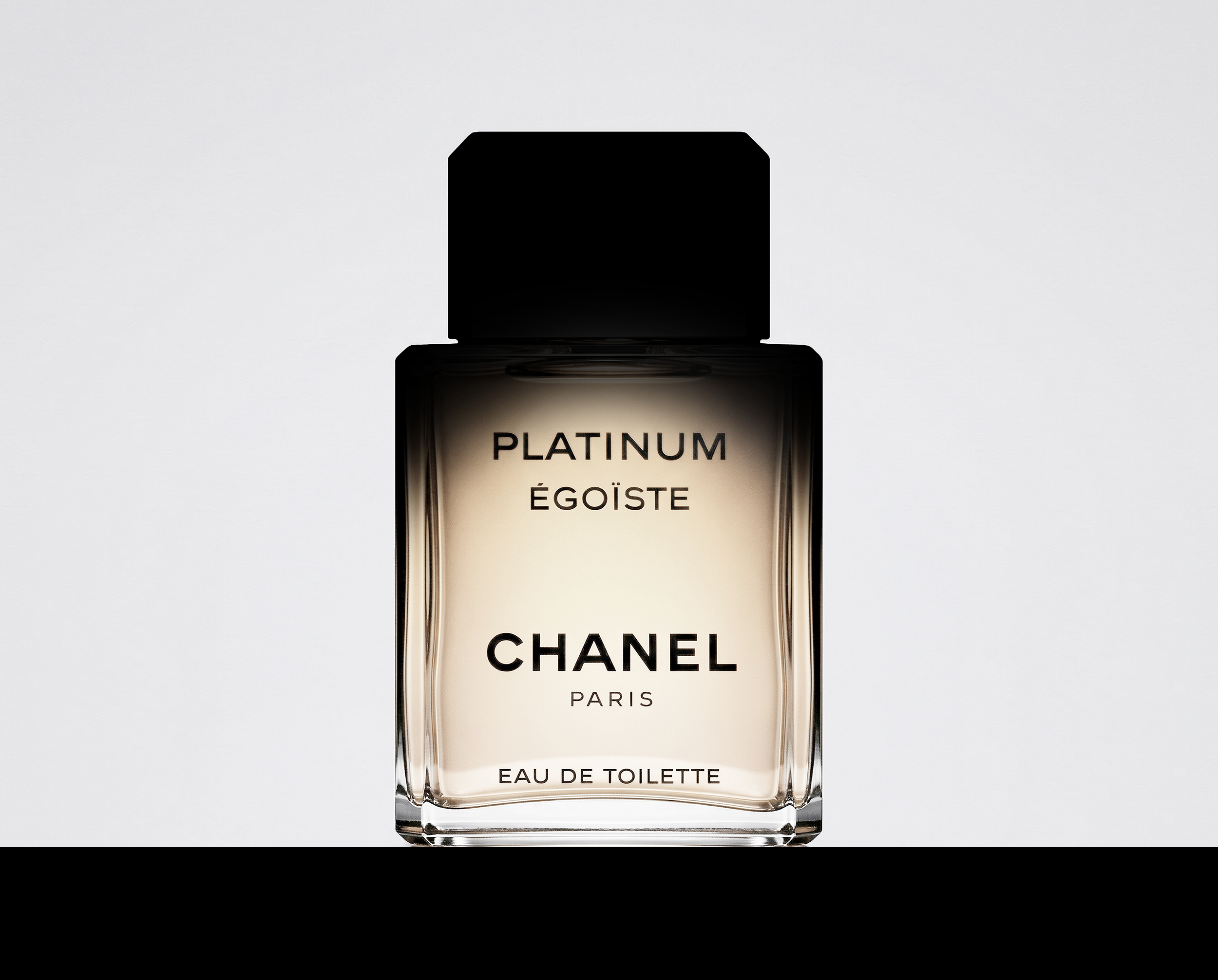 A bottle of Chanel Coco Mademoiselle perfume with a minimalist design and black cap, set against a light background.