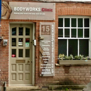 Exterior view of a Body Works Clinic with a door, a window, and a vertical sign displaying services and contact information. Bodyworks is the home of Fineline Counselling in Chalfont St Peter