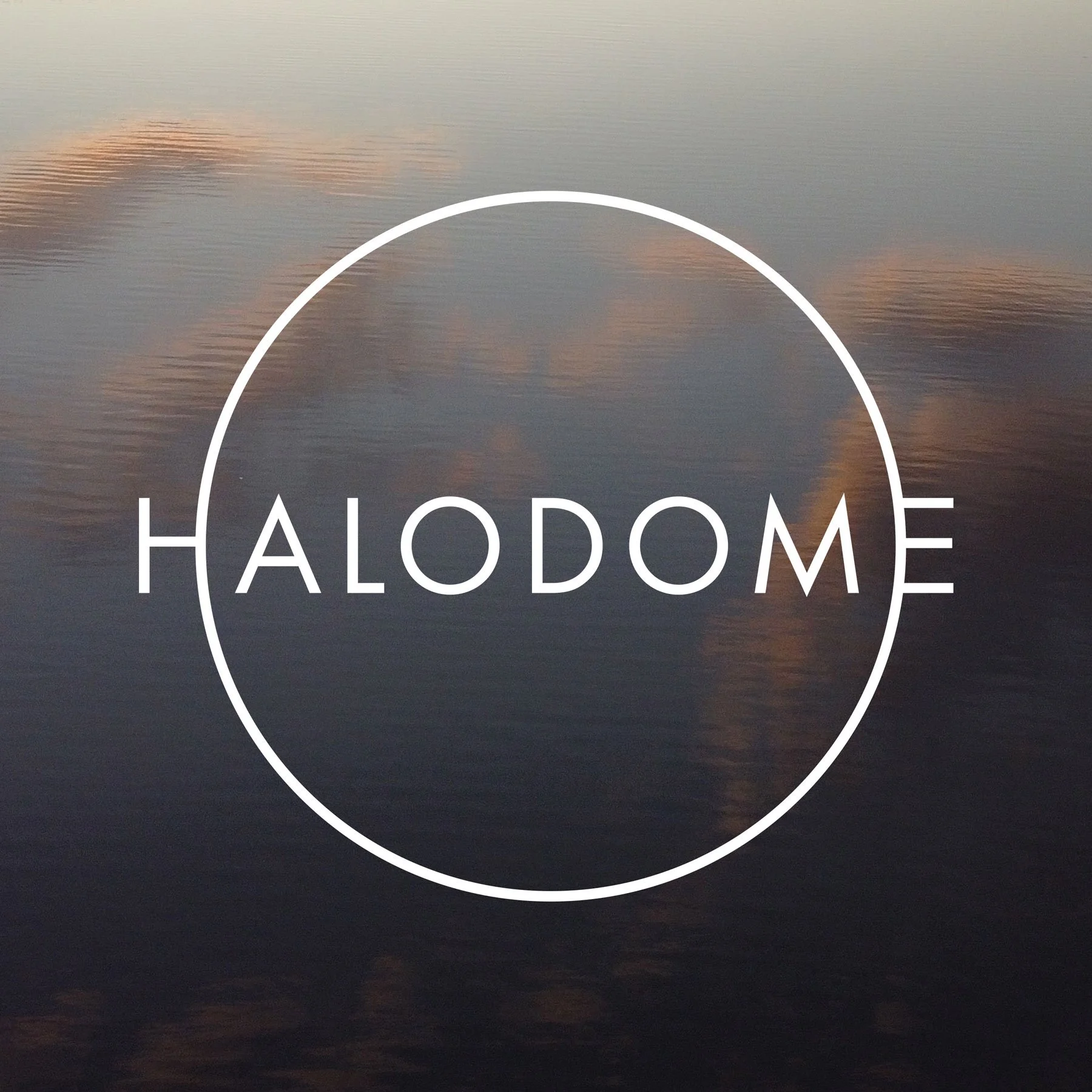Kuva auringonlaskusta tai -noususta järvellä, jossa on pilviä taivaalla, ja teksti 'HALODOME' keskellä