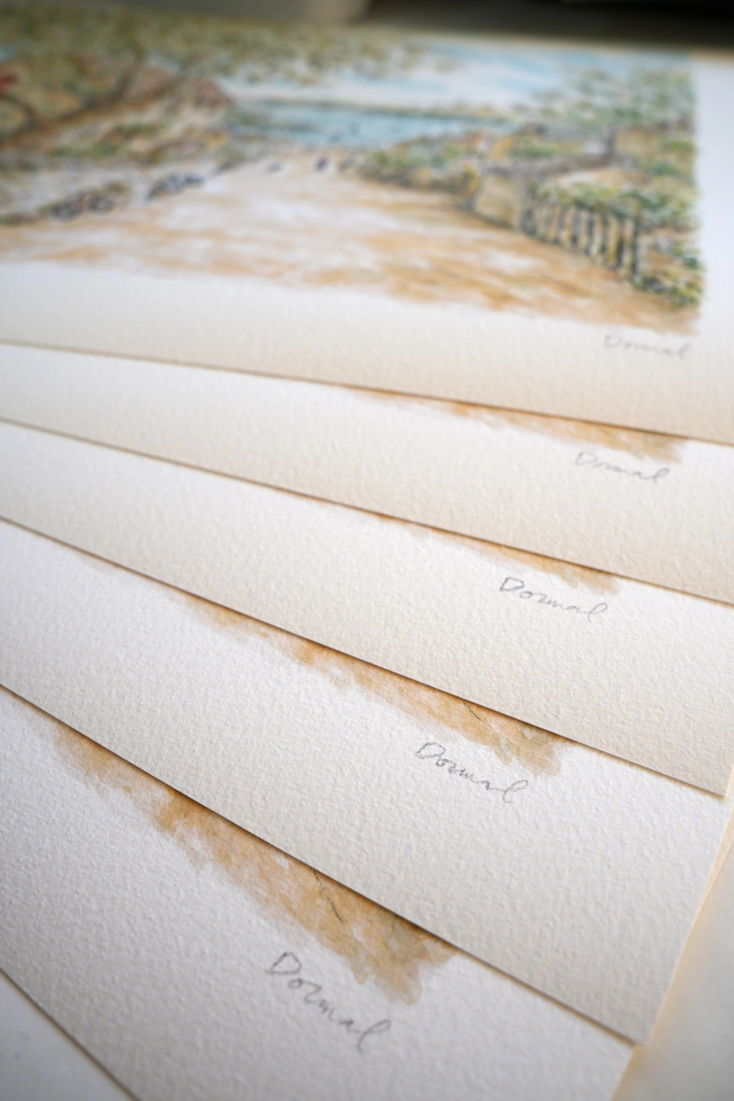 Tirages d'art sur papier d'art texturé avec signatures, présentant des œuvres d'art ou des illustrations, avec une image floue d'une peinture de paysage en haut.