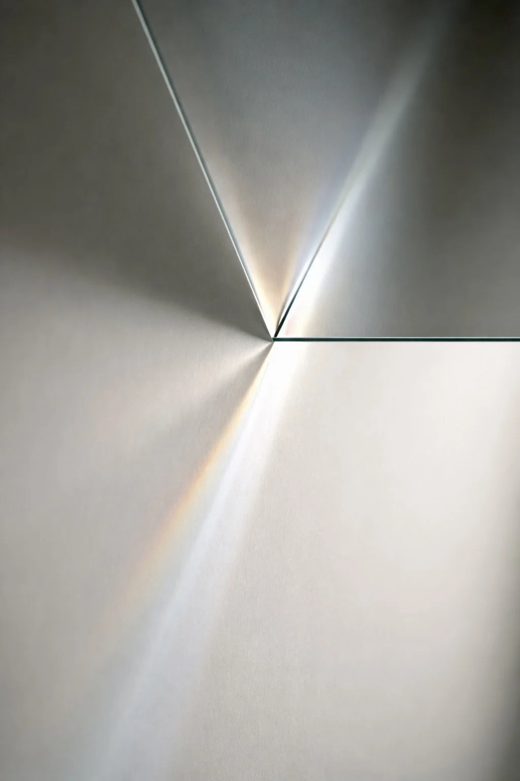 Close-up of a geometric metallic object with intersecting reflective surfaces, creating light reflections and shadows.