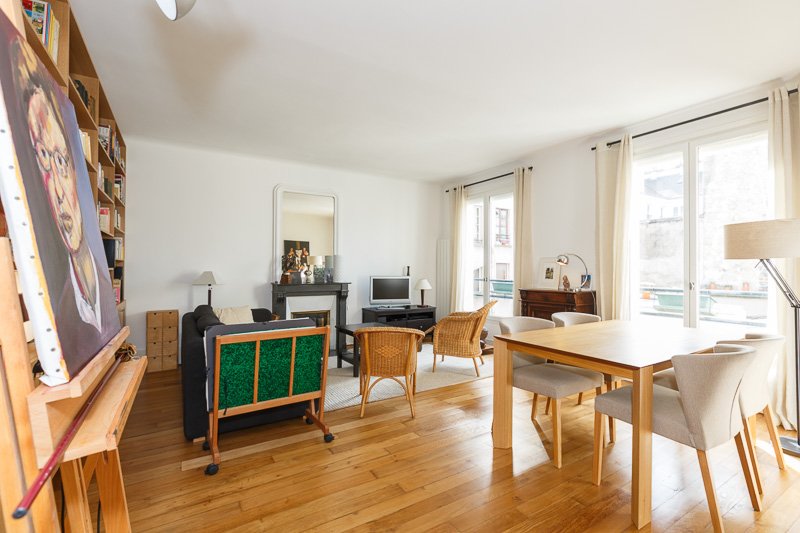 Espace salle à manger d'un séjour lumineux aux nombreuses fenêtres dans un appartement à la frontière du Marais