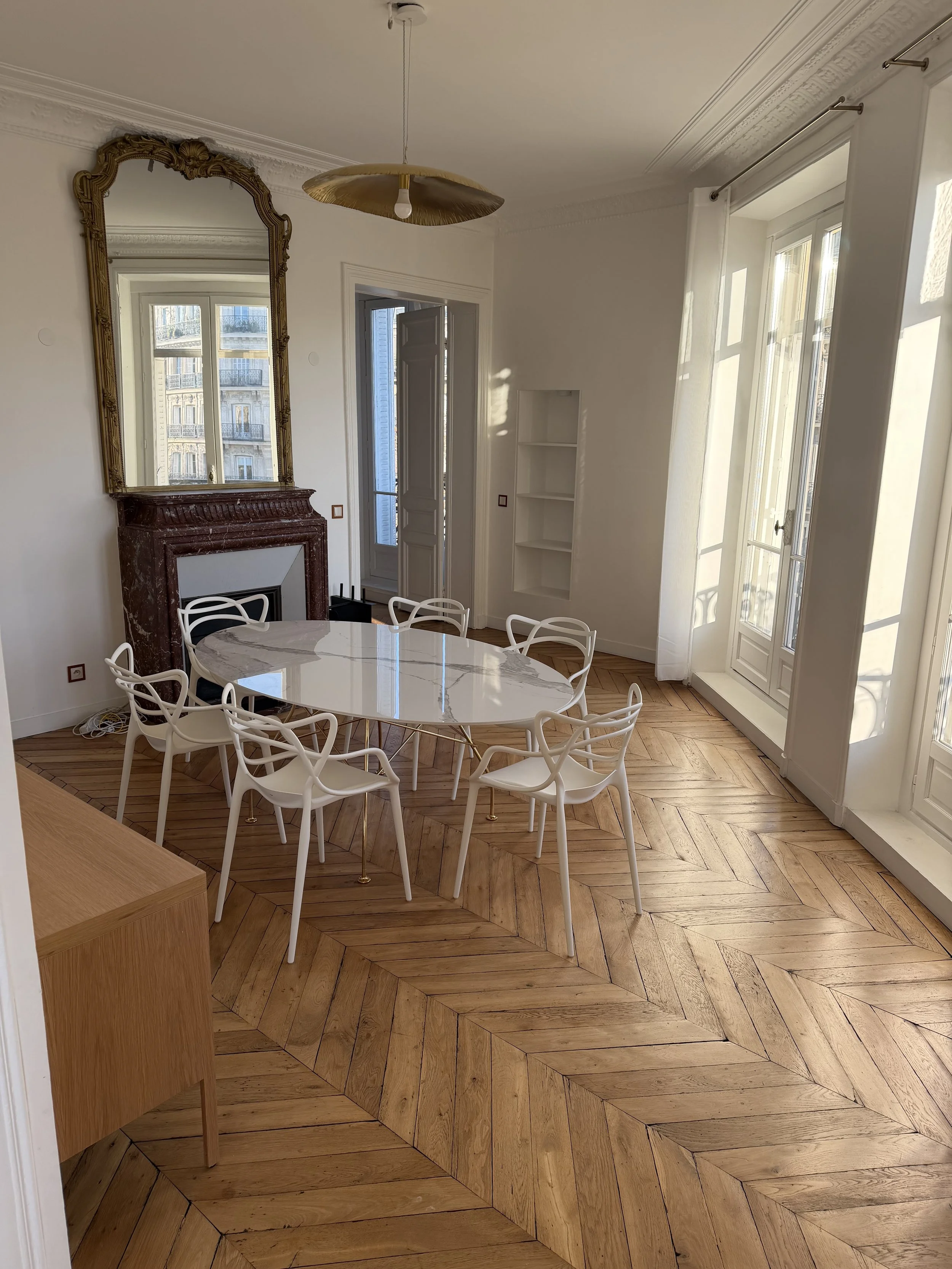 Salle à manger avec parquet point de Hongrie, cheminée, moulures et balcons