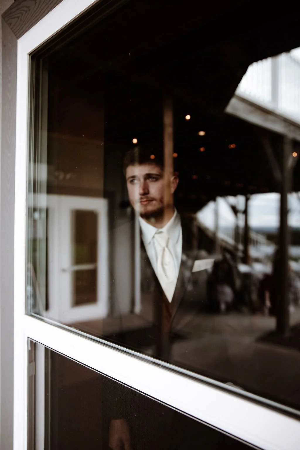 A man in formal attire looking out a window.