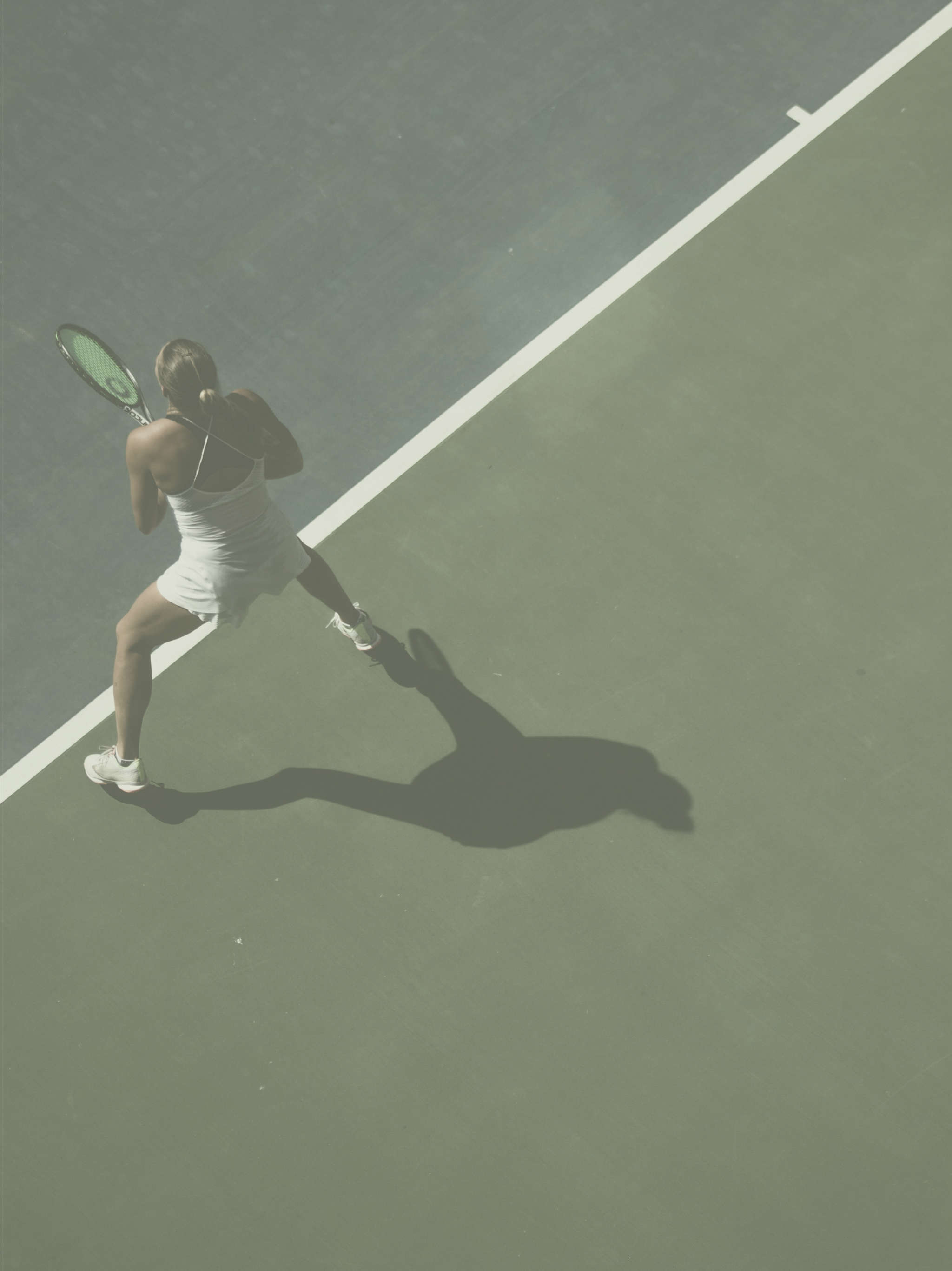 A woman playing tennis on a court, wearing a white athletic outfit, holding a tennis racket, with her shadow cast on the court.