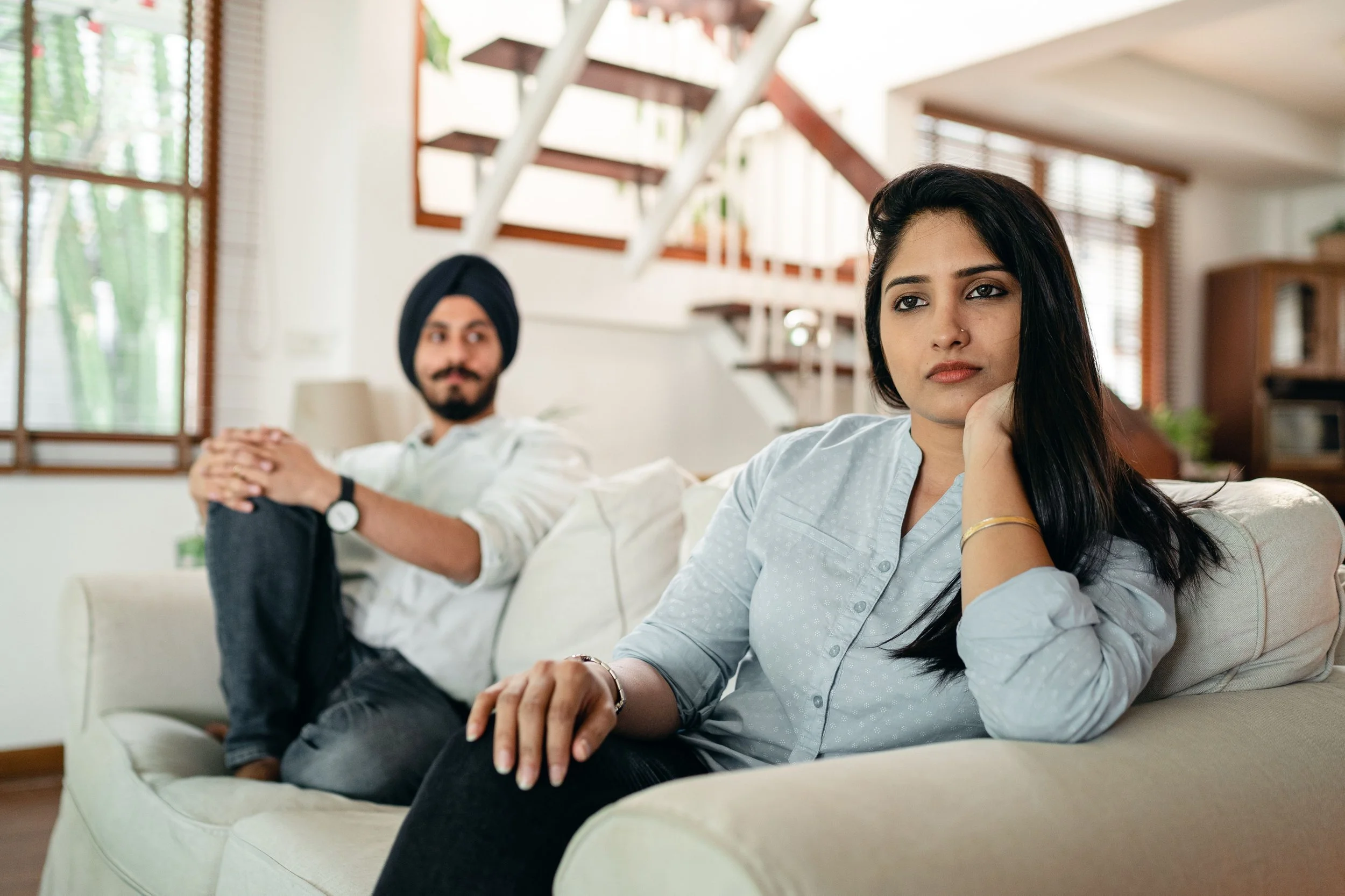 Couple sitting together after an argument feeling emotionally disconnected while avoiding eye contact.