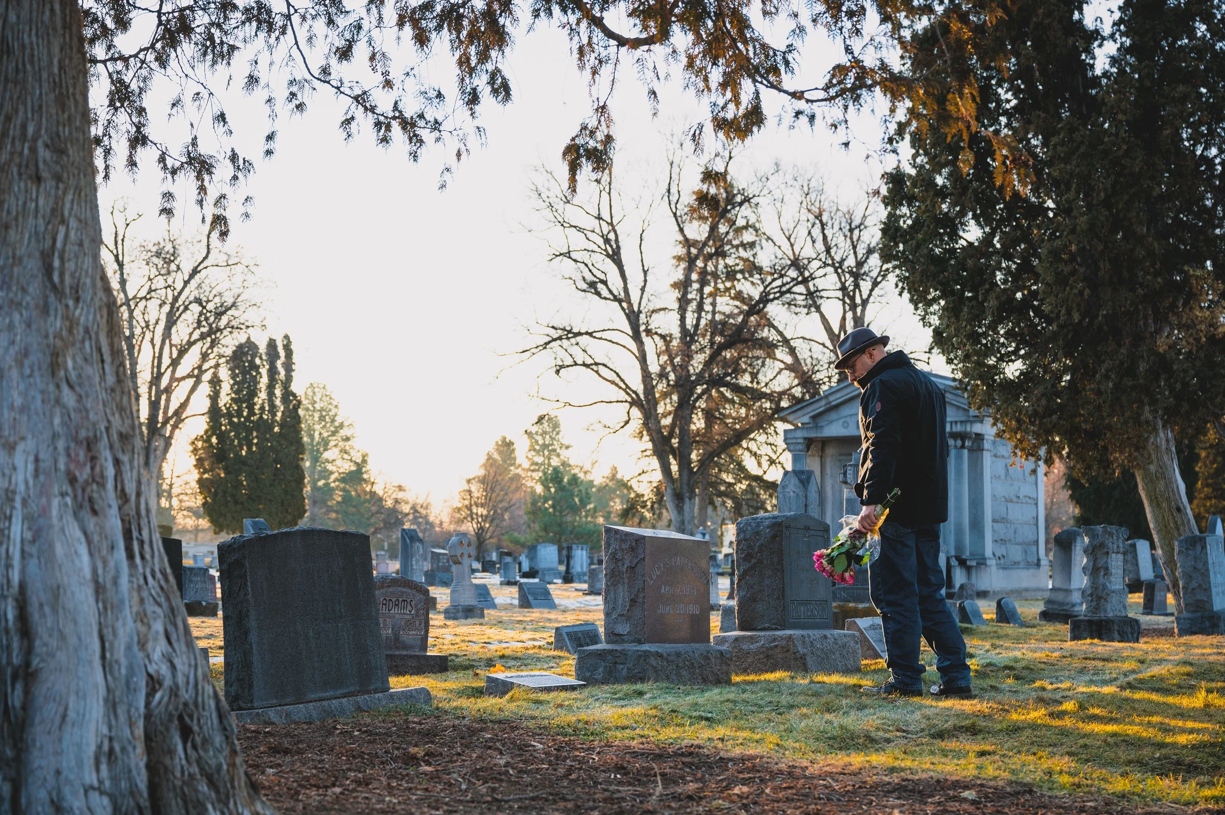 Gentleman visiting a loved ones at the cemetery grieving.
