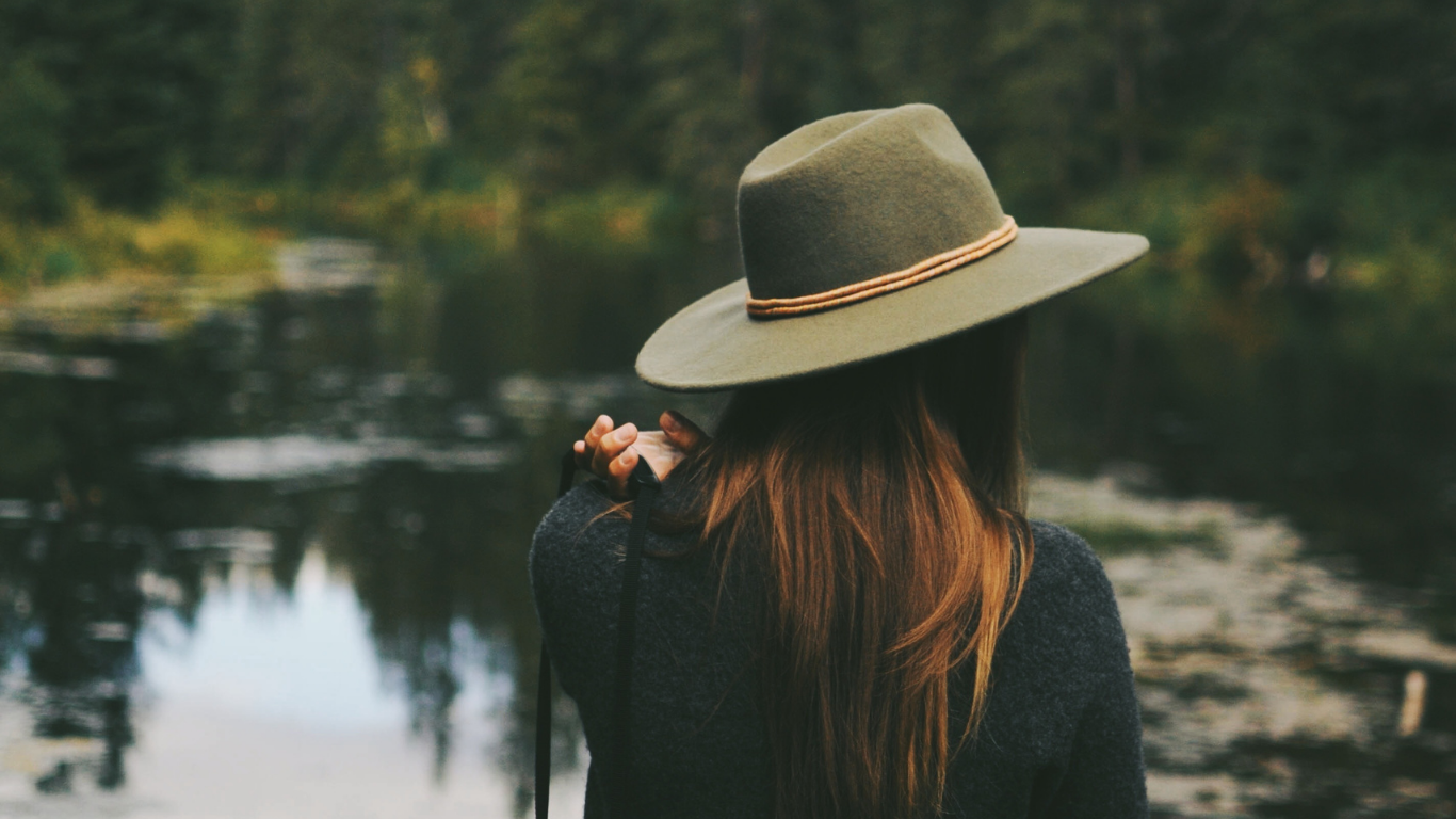 Woman with hat sitting near pond, anxiety therapy in East Greenwich RI