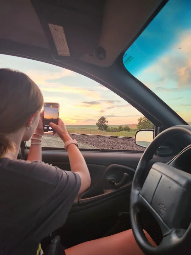 20240708_genevieve taking a sunset pic from car.jpg