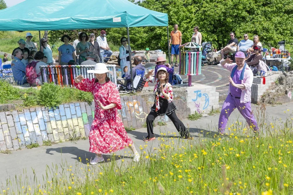 Three community dancers leaning to one side outdoors.