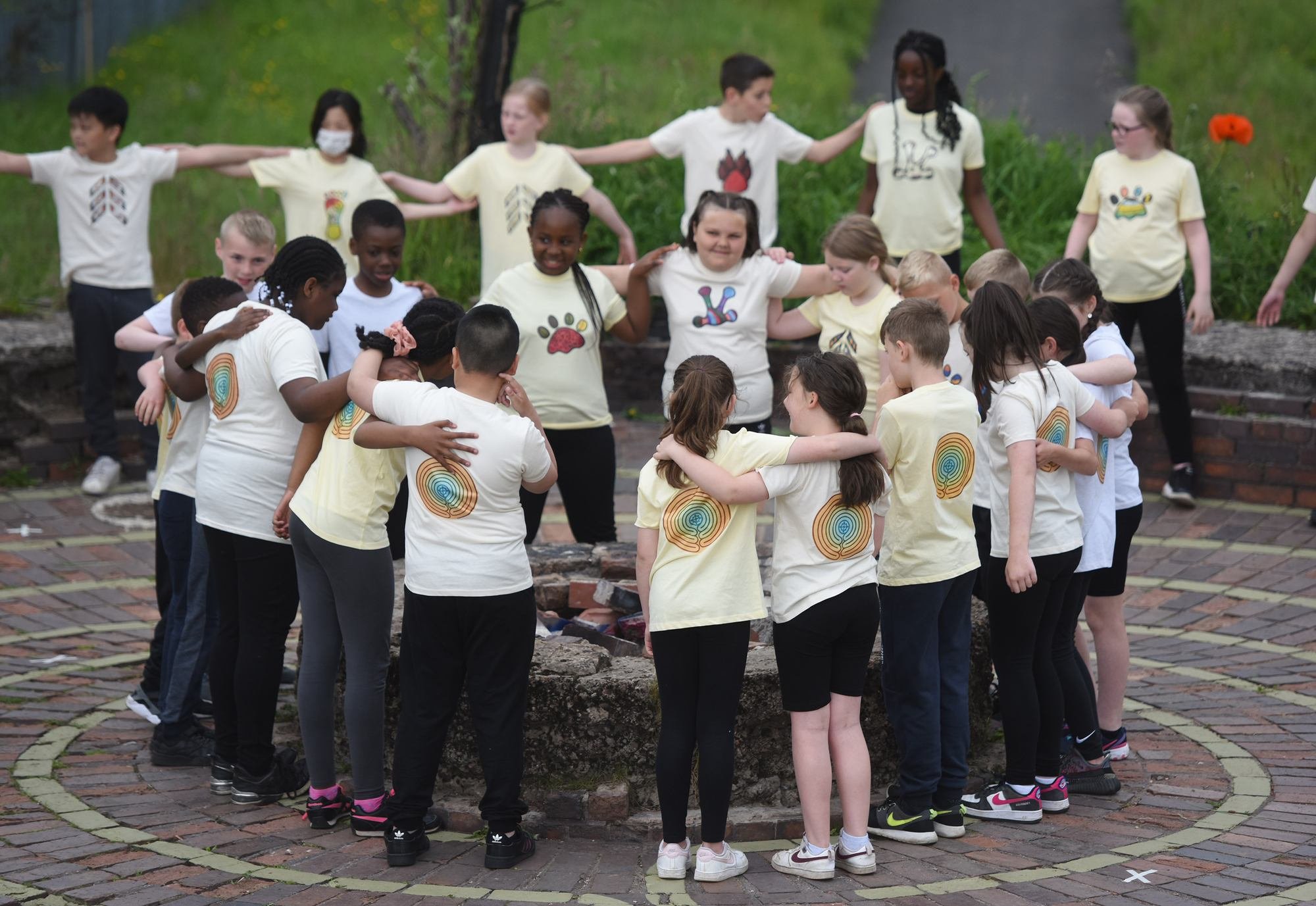A group of children standing in a circle linked by arms.