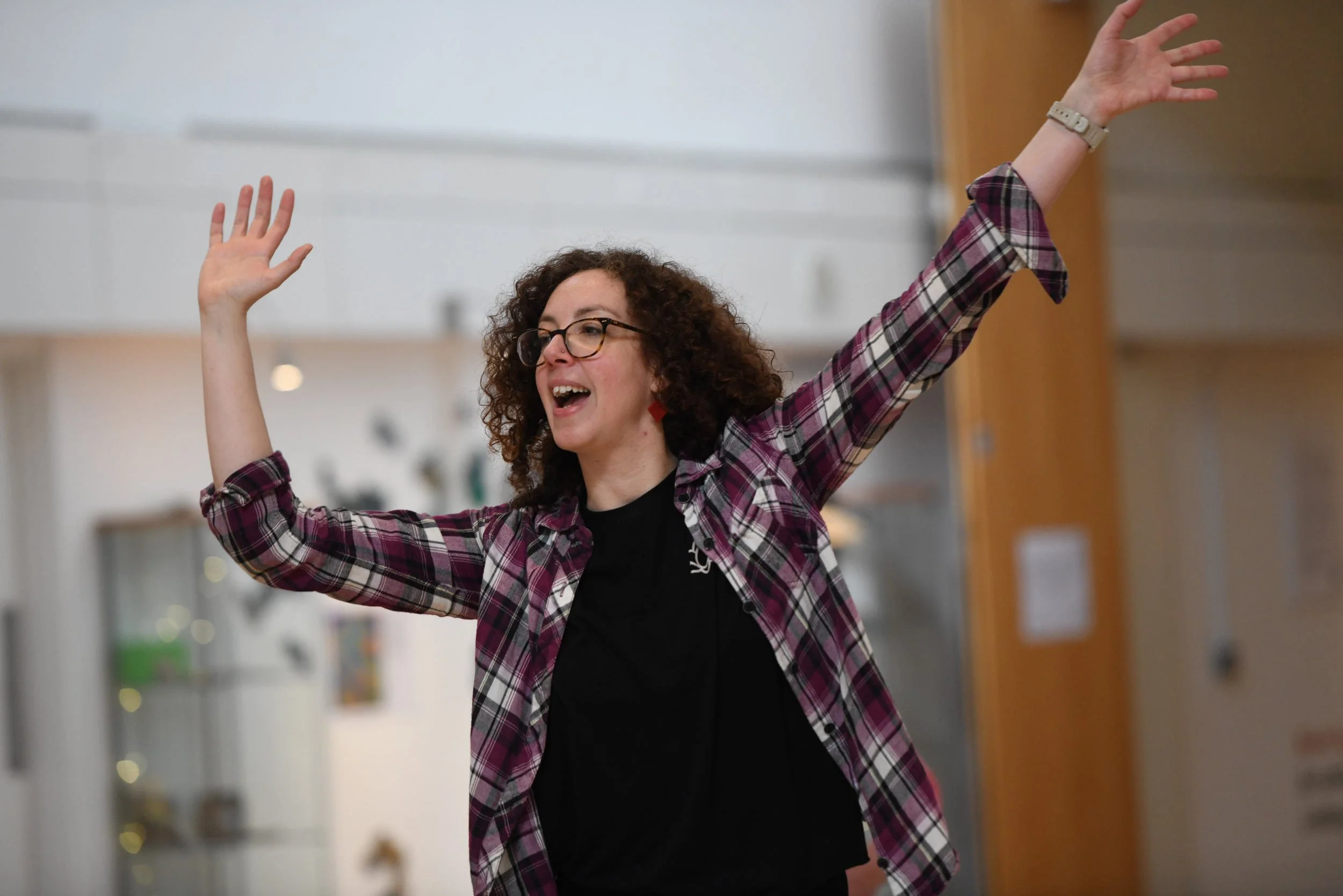 Saffy Setohy, dance artist, arms raised joyfully while leading a movement session at Macrobert Arts Centre.