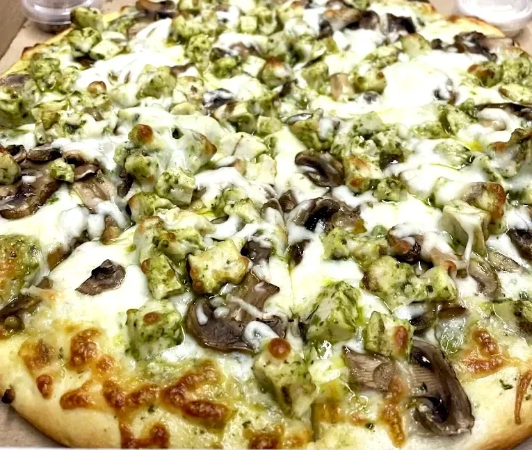Close-up of a pizza topped with artichoke hearts, mushrooms, and melted cheese.