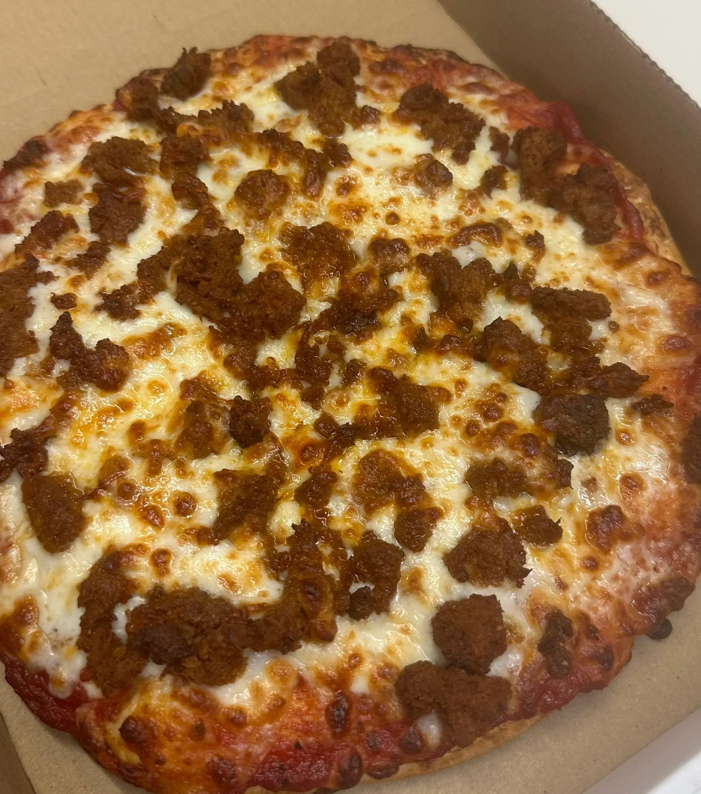 A slice of pizza with sausage and cheese on a pizza crust.