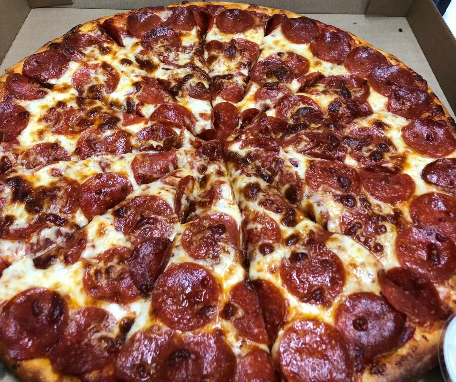 A pepperoni pizza with cheese in a cardboard delivery box.