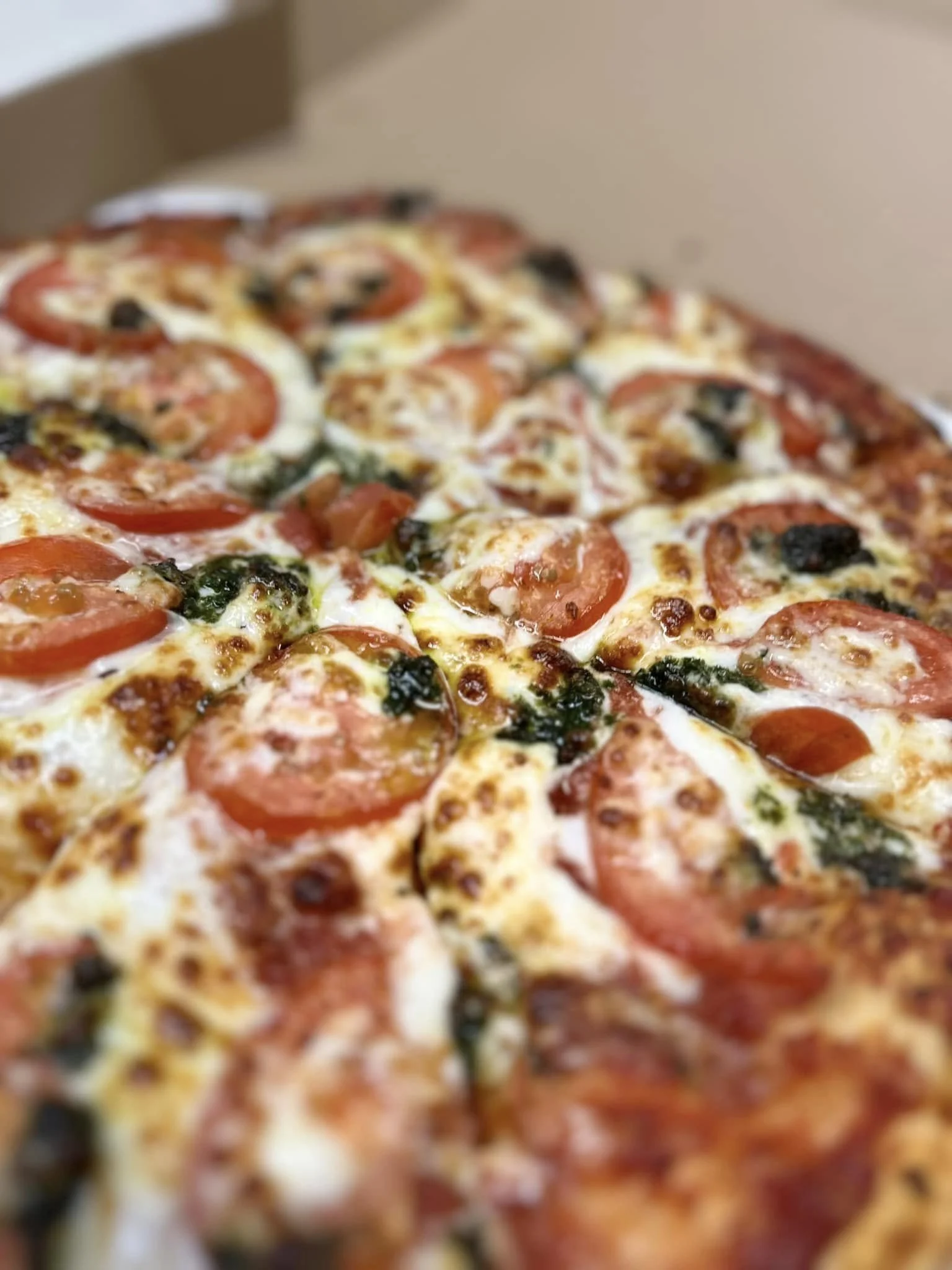 Close-up of a freshly baked pepperoni and cheese pizza in a cardboard box.