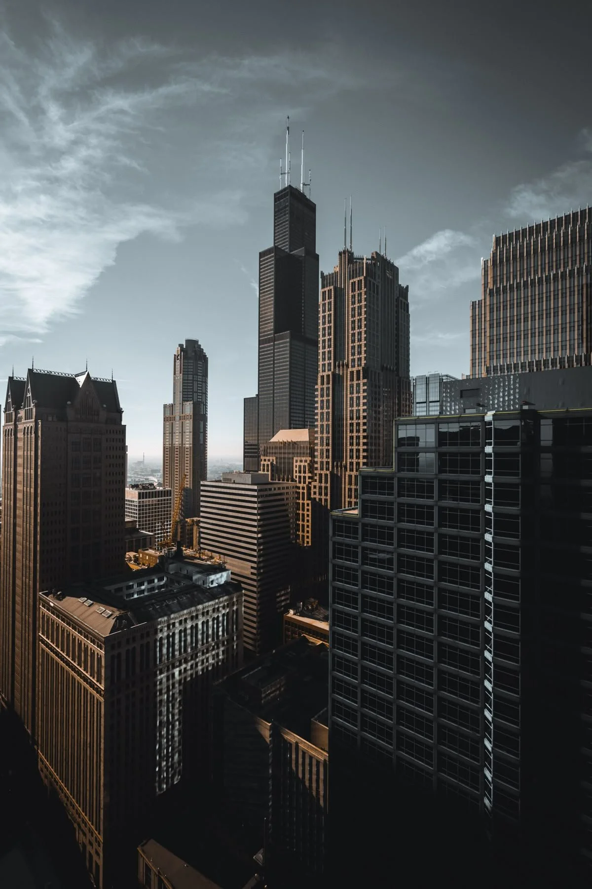 City skyline with tall skyscrapers, including the Willis Tower, under a cloudy sky.