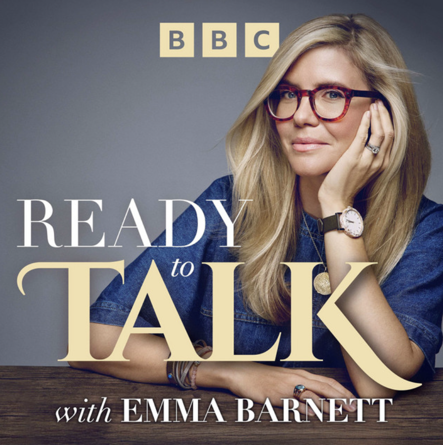 Cover photo of Emma Barnett for the podcast "Ready to Talk" with the BBC logo above. Emma Barnett is wearing glasses, a watch, and a denim shirt, sitting at a wooden table with a thoughtfully pose.
