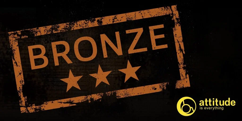 A graphic design with a grunge style showing the word 'BRONZE' in large orange letters and three orange stars below it, on a dark background. The bottom right corner has a yellow logo and the text 'attitude is everything'.