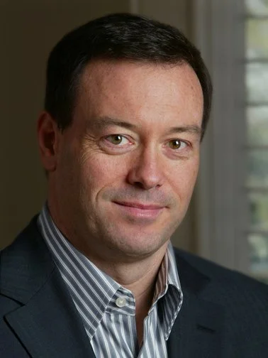 A man with black hair wearing a striped shirt and suitcoat