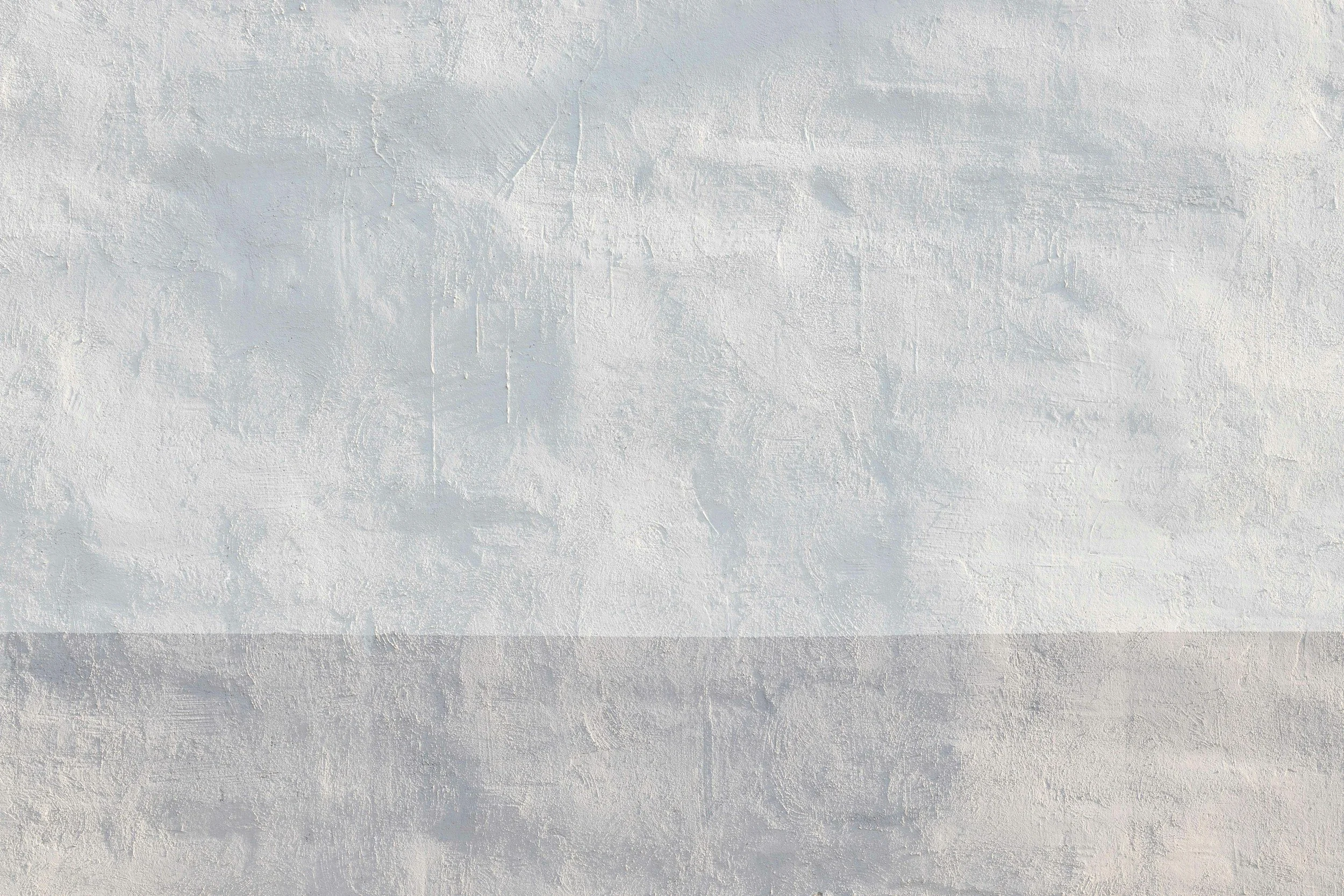 White and gray textured wall surface with subtle color variation and visible brush strokes.