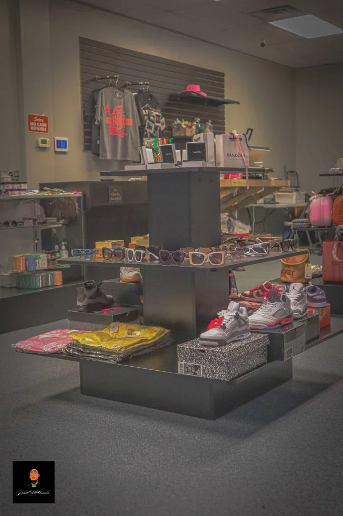 Display of sunglasses, sneakers, and folded clothing in a retail store.