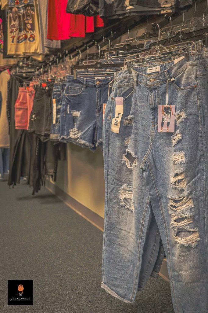 A display of distressed and ripped blue jeans hanging on a clothing rack in a store.