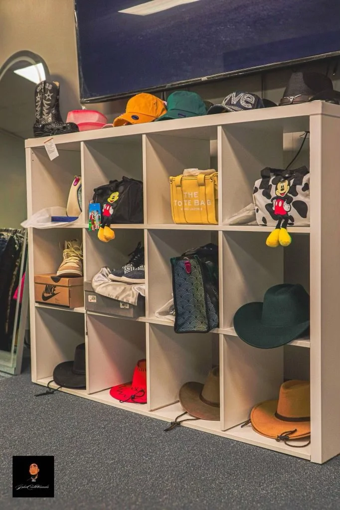 White cubby shelf holding shoes, hats, bags, and a Mickey Mouse stuffed toy, with hats on top and items inside the cubbies.