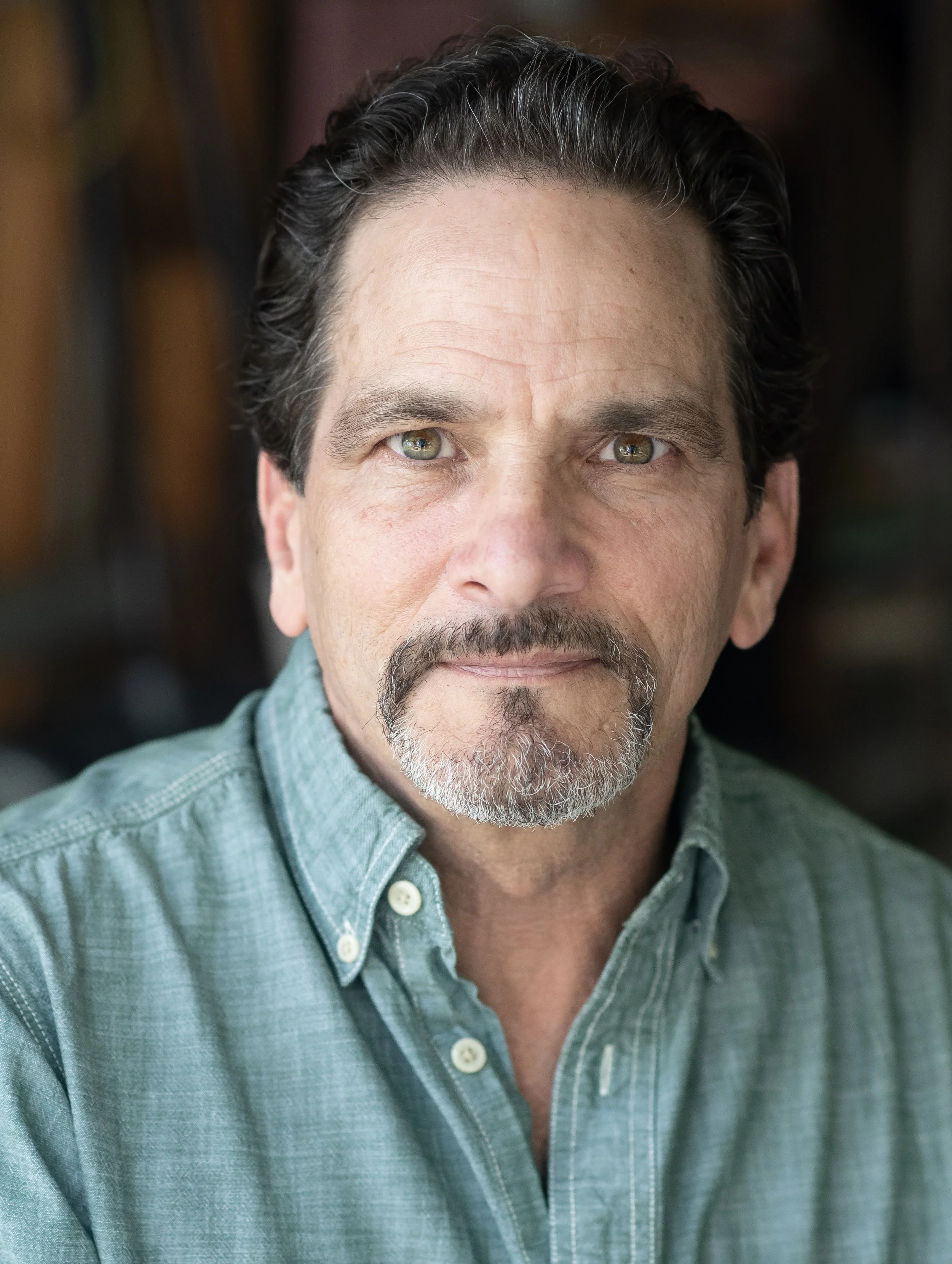 Author James DeVita in a teal button-down shirt, photographed against a warm, softly blurred background