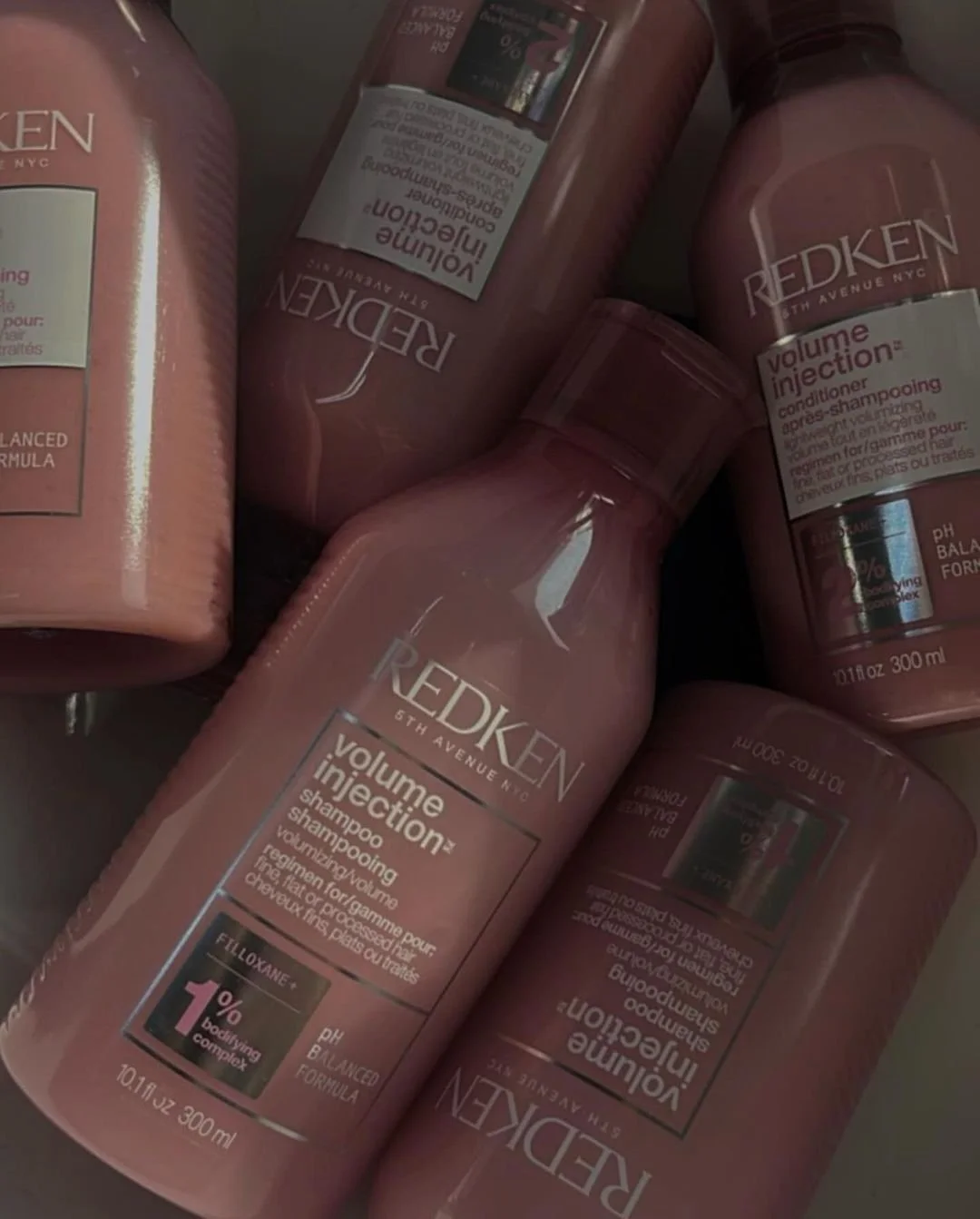 Pink bottles of Redken Volume Injection shampoo and conditioner.