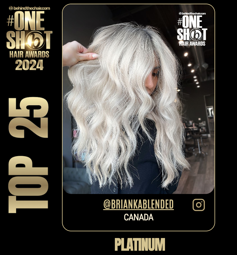 Woman with platinum blonde wavy hair at the 2024 Behind the Chair #OneShot Hair Awards, holding her hair with her right hand, in a salon setting, wearing a black shirt, with the Instagram handle @briankablended and Canadian location, celebrating platinum hair.
